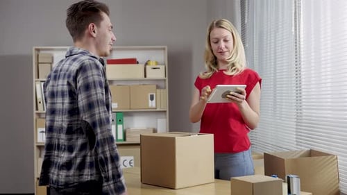 Female Warehouse Worker Online Store Owner Gives the Man to the Courier a Cardboard Box of the