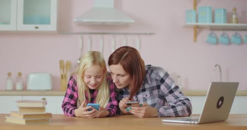 Child and Woman Use Smartphones in Kitchen