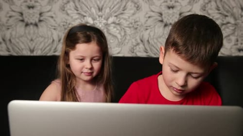 Two Children Looking at a Laptop at Home