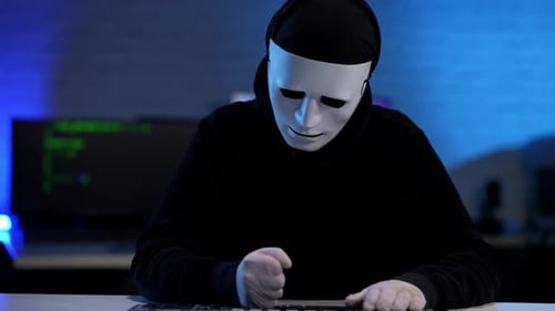 Nervös gestresster unkenntlicher Hacker in schwarzer Kleidung und anonymer Maske schlägt Tisch mit Fäusten