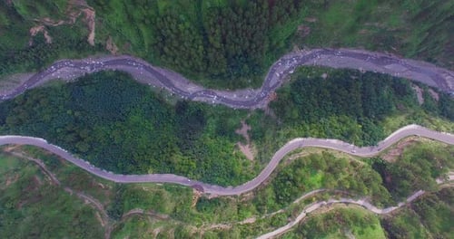 Luftflug über das Auto, das die Straße entlang fährt, umgeben von Wald, eine geschwungene, kurvenreiche Straße