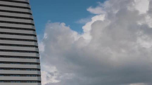 Skyscraper Balconies and Windows Against Blue Sky and Moving Clouds