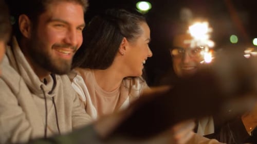 Happy Friends with Sparklers at Night Outdoors