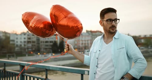 Romantic Couple Embrace Holding Red Heart Balloons