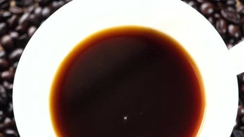 Black Coffee in a Cup Surrounded by Beans