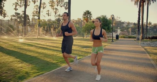 Couple Jogging Together in Park at Sunrise