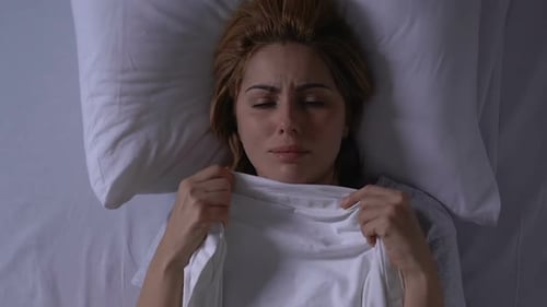Femme qui pleure allongée dans son lit tenant une couverture, problèmes de santé et de vie, dépression