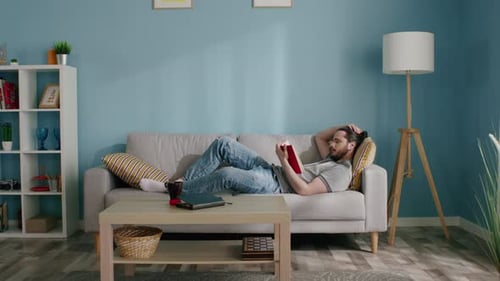 Man Reading Book Relaxing at Home on Couch