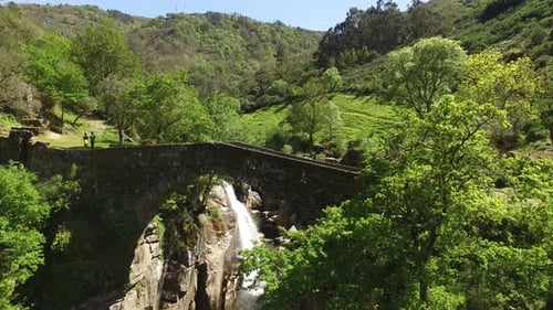 Picturesque Stone Bridge Over Waterfall in Lush Nature