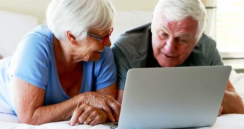 Mature Couple Watching Laptop Together on a Bed