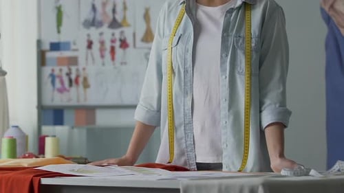Atelierbesitzerin schaut sich Designskizzen von Abendanzügen und Kleidern an