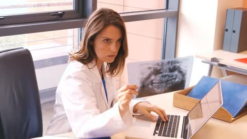 Doctor Analyzes X-Ray Image While Working on Laptop