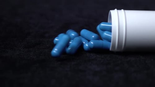 Medicine Blue Pills Fall Down on Black, Slow Motion, Close Up