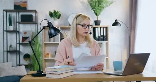Empresaria con auriculares sentada frente a una computadora portátil en una acogedora oficina en casa durante una videoconferencia