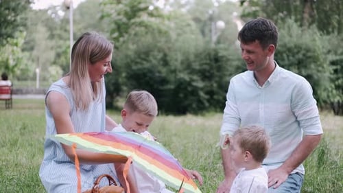 Parents and Two Sons Are Sitting on the Grass in the Park