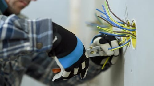 Man Cuts Wires In Electrical Outlet.