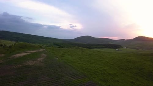 Aerial view of a wide valley while the sun is setting behind the mountains in the background, Transy