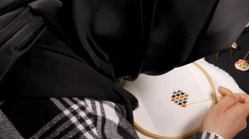 Woman Carefully Cross-Stitching a Colorful Geometric Design