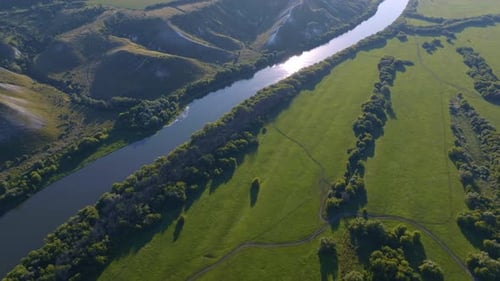 Aerial Footage of a Large River Surrounded By Green Fields and Hills