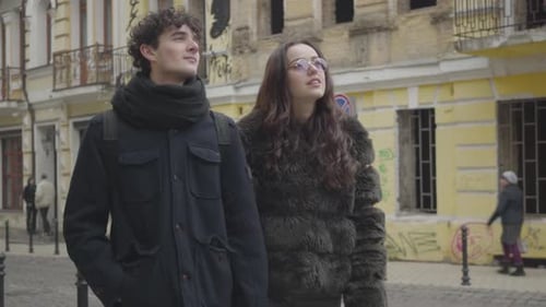 Portrait of Happy Young Caucasian Couple Walking on City Street and Chatting. Positive Boy and Girl