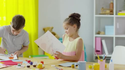 Little Boy and Girl Cutting Out Painting in Art Class