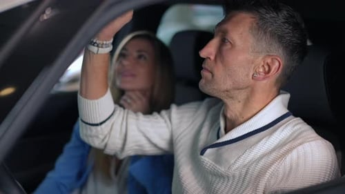 Side View Concentrated Successful Man on Driver's Seat Examining Car with Blurred Smiling Woman