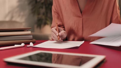 Woman Reviewing Documents and Writing at Desk