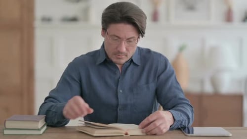 Young Man Reading Book while Sitting in Office