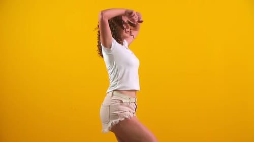 Young Woman Dances with Energy on Yellow Background