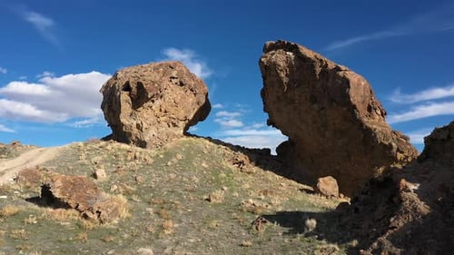 Aerial flying up and through gap between boulders in the desert