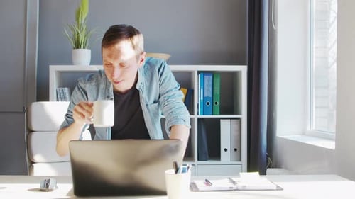 Young male entrepreneur works at home office at the computer.