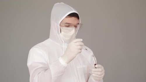 O cientista em equipamentos de cobertura total está coletando sangue de um teste com uma seringa