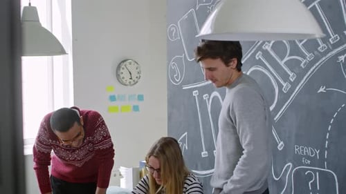 Cheerful Woman Working on Laptop with Male Colleagues in Office