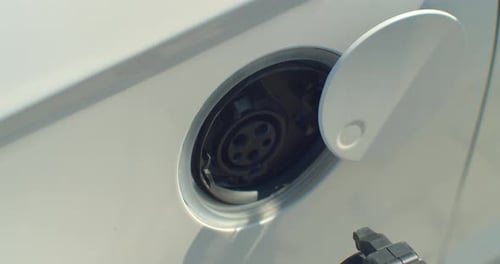 Close Up Of Hand Attaching Power Cable To Environmentally Friendly Zero Emission Electric Car.