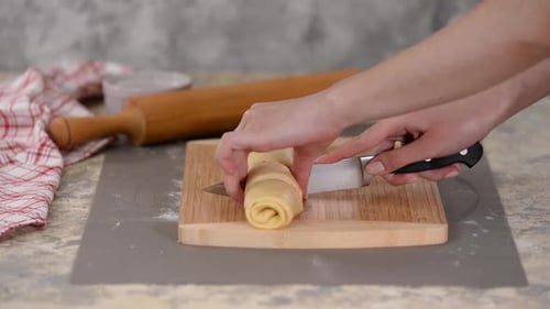 Woman Cuts Rolled Dough Log into Slices