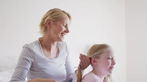 Side view of Caucasian woman brushing hair of her daughter