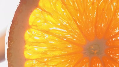 Una gota de agua fluye por la superficie de una jugosa rodaja de naranja madura