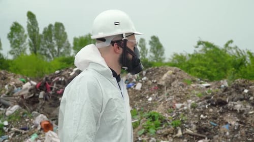Man in Protective Suit at Landfill Looks at Camera