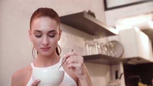 Young Woman Eating From Bowl in Kitchen