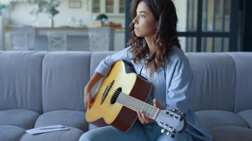 Young Woman Playing Guitar and Writing Music