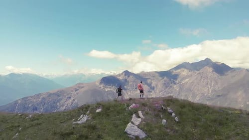 Aerial slow motion: couple backpackers hiking on mountain top, scenic landscape