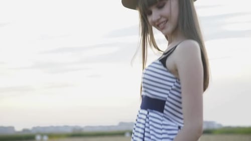 Glamorous Model Poses with Hat in Wheat Field at Camera