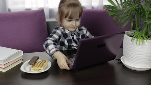 Young Girl Typing on Purple Laptop at Home