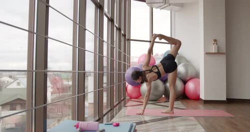 Athletic Woman Stretching on a Mat in a Fitness Studio