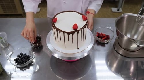 Chef Decorating White Cake with Chocolate and Berries