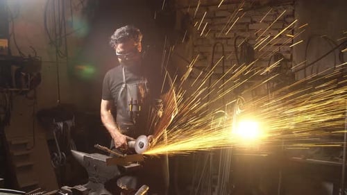 Mann arbeitet am Winkelschleifer in der Werkstatt. Schmied arbeitet mit Metall
