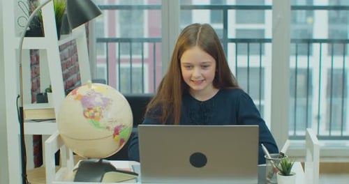 Girl Learning at Laptop with Globe at Desk