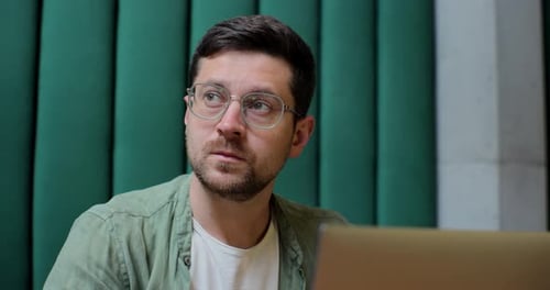 Man Sits in Cafe in Daytime and Using the Laptop for the Remote Work