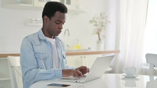 Young Adult Male Working at Table with Laptop
