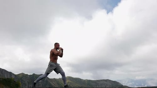 Man Practicing Fighting Moves in Mountain Setting